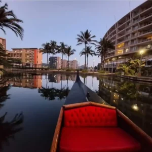 View from the red seat of a Zulumoon gondola on a quiet canal, inviting you to book weekend boat rides in Durban.