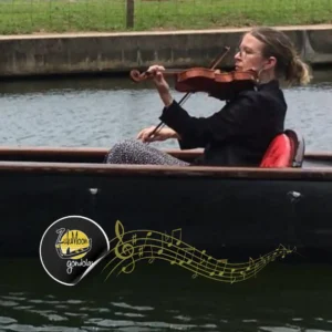 A violinist plays live music from a separate boat to accompany a deluxe and romantic luxury boat cruise experience.