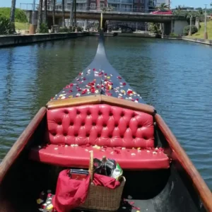 A luxury boat cruise package setup featuring a picnic basket and rose petals on a private gondola.