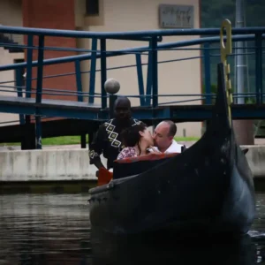 A newly engaged couple shares a kiss on a romantic boat ride in Durban under a waterfront bridge.