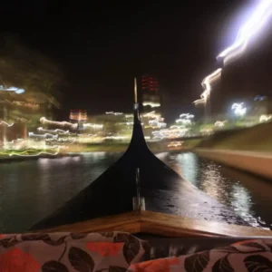 A view from the front of a gondola boat ride in Durban at night with city lights reflecting on the water.